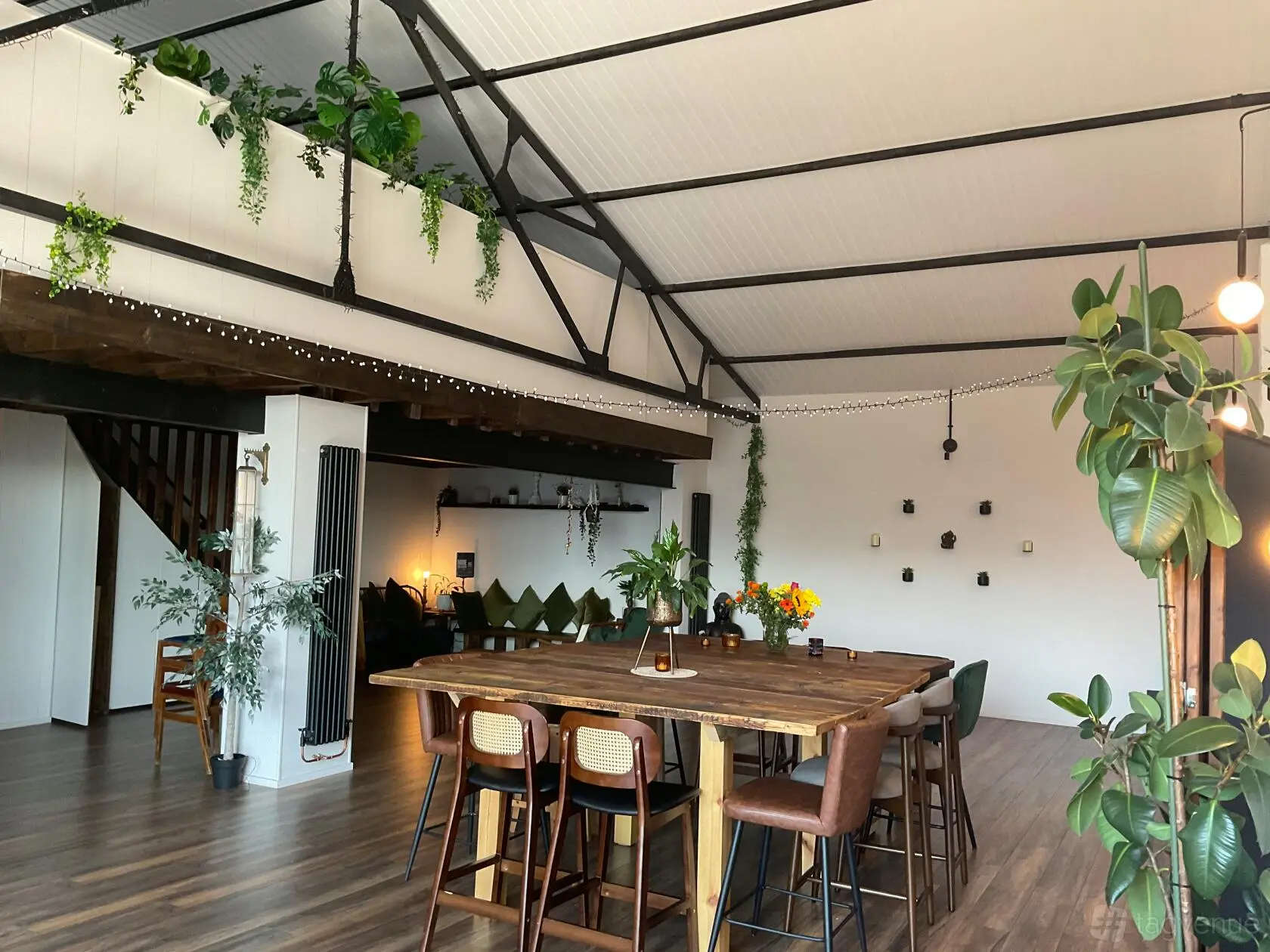 The long dining table beneath the high industrial roof