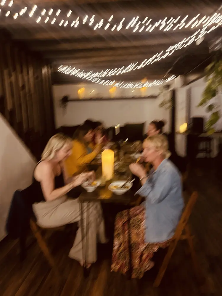 Friends sharing a candlelit meal under string lights